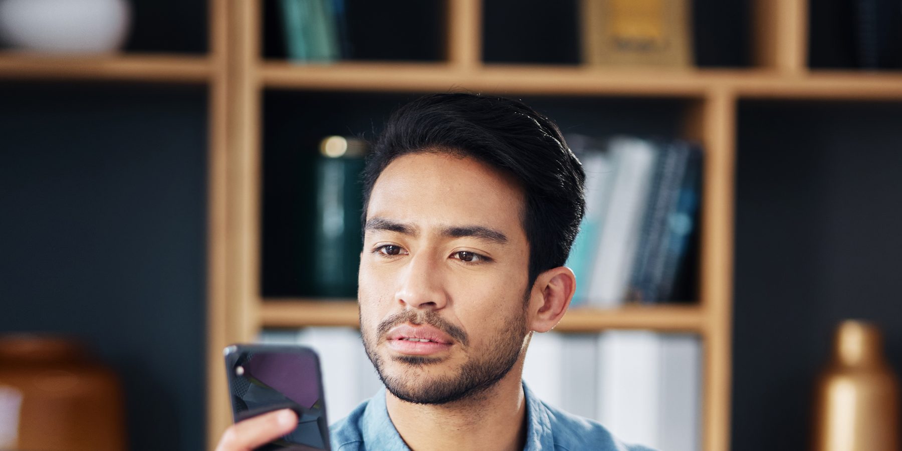 A man comparing something on his phone beside a laptop
